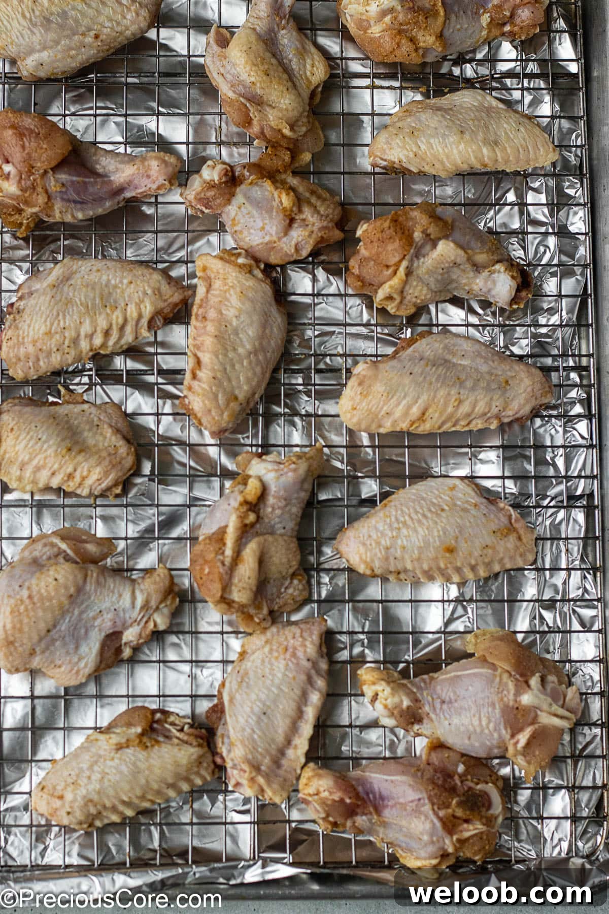 Raw chicken on a rack placed on a baking sheet.