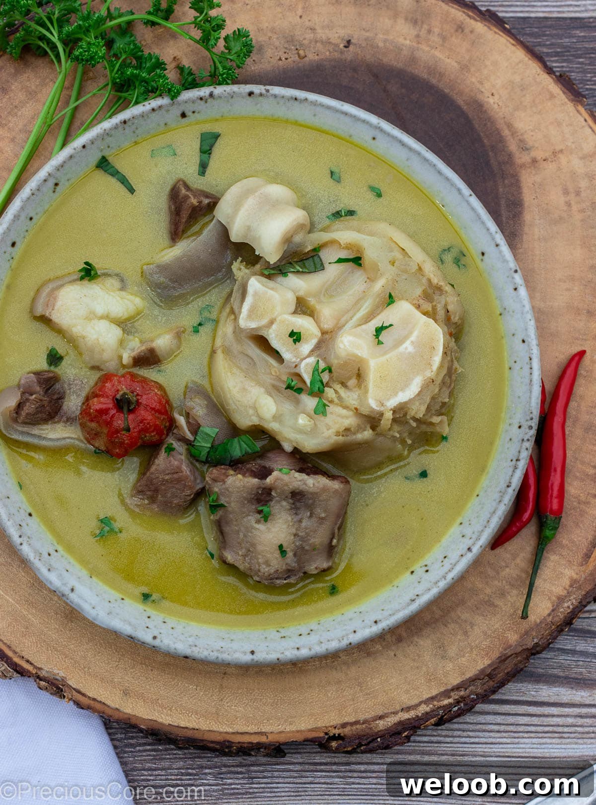 Bowl of pepper soup sitting on a round platter.
