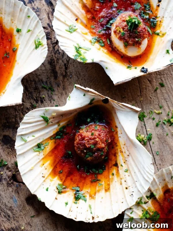 An overhead shot of scallops in their shells with a Nduja garlic butter on top.