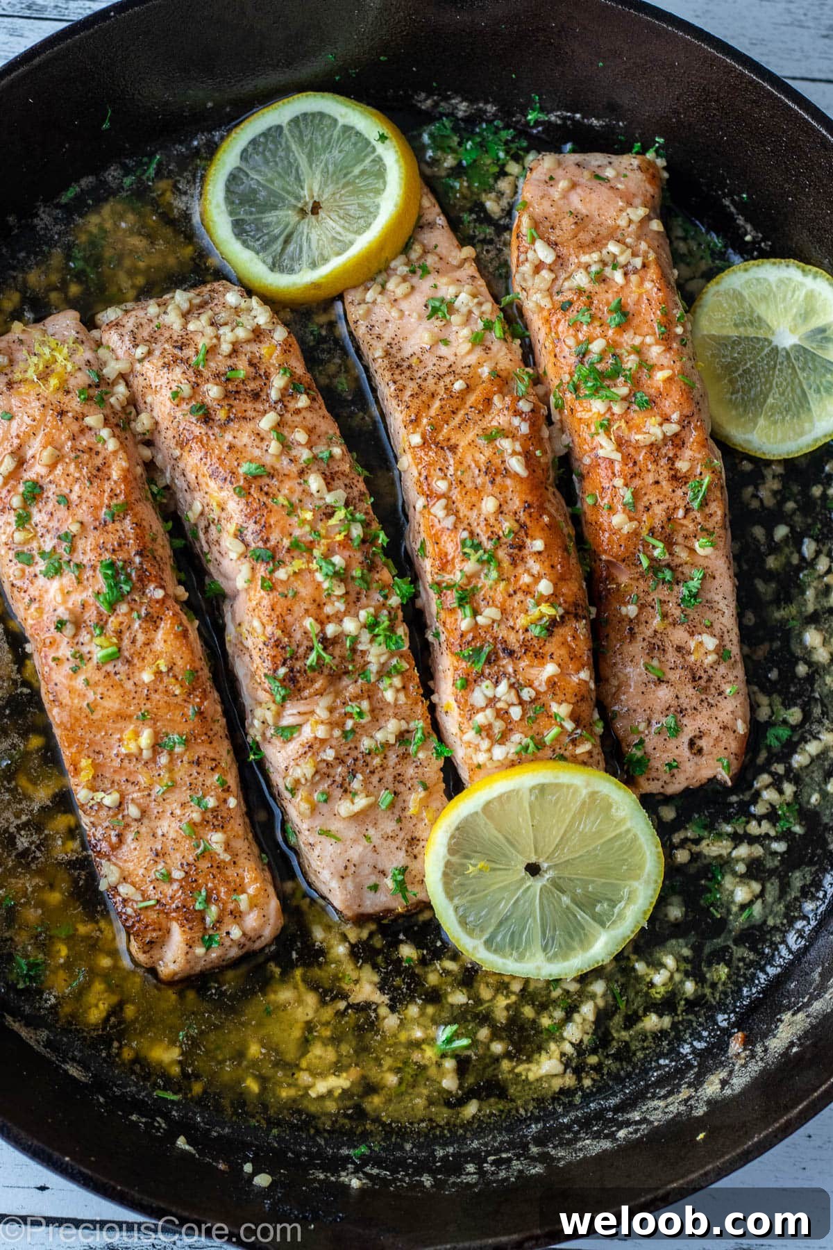 Pan-Seared Lemon Butter Salmon with Garlic and Herbs 2 4 pieces of salmon in a cast iron skillet.