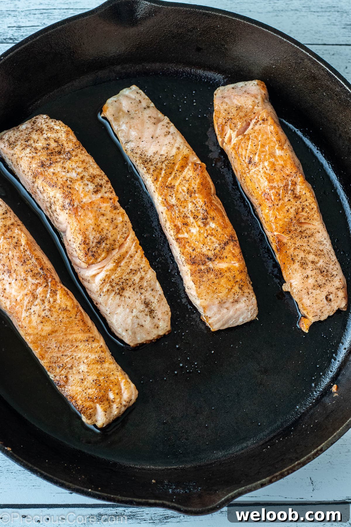 Pan-Seared Lemon Butter Salmon with Garlic and Herbs 5 Seared salmon fillets in a cast iron skillet.