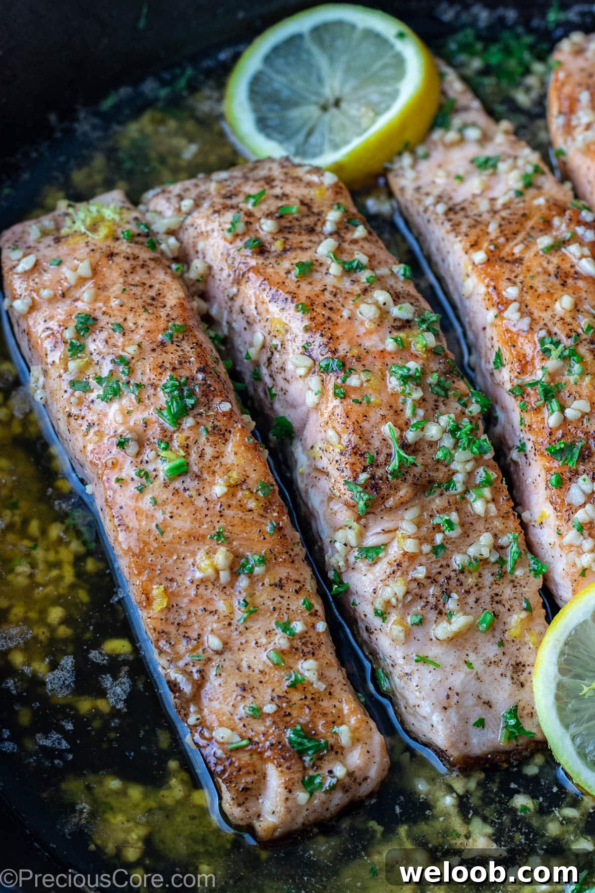 Pan-Seared Lemon Butter Salmon with Garlic and Herbs 7 Lemon butter salmon in pan garnished with parsley and lemon slices.