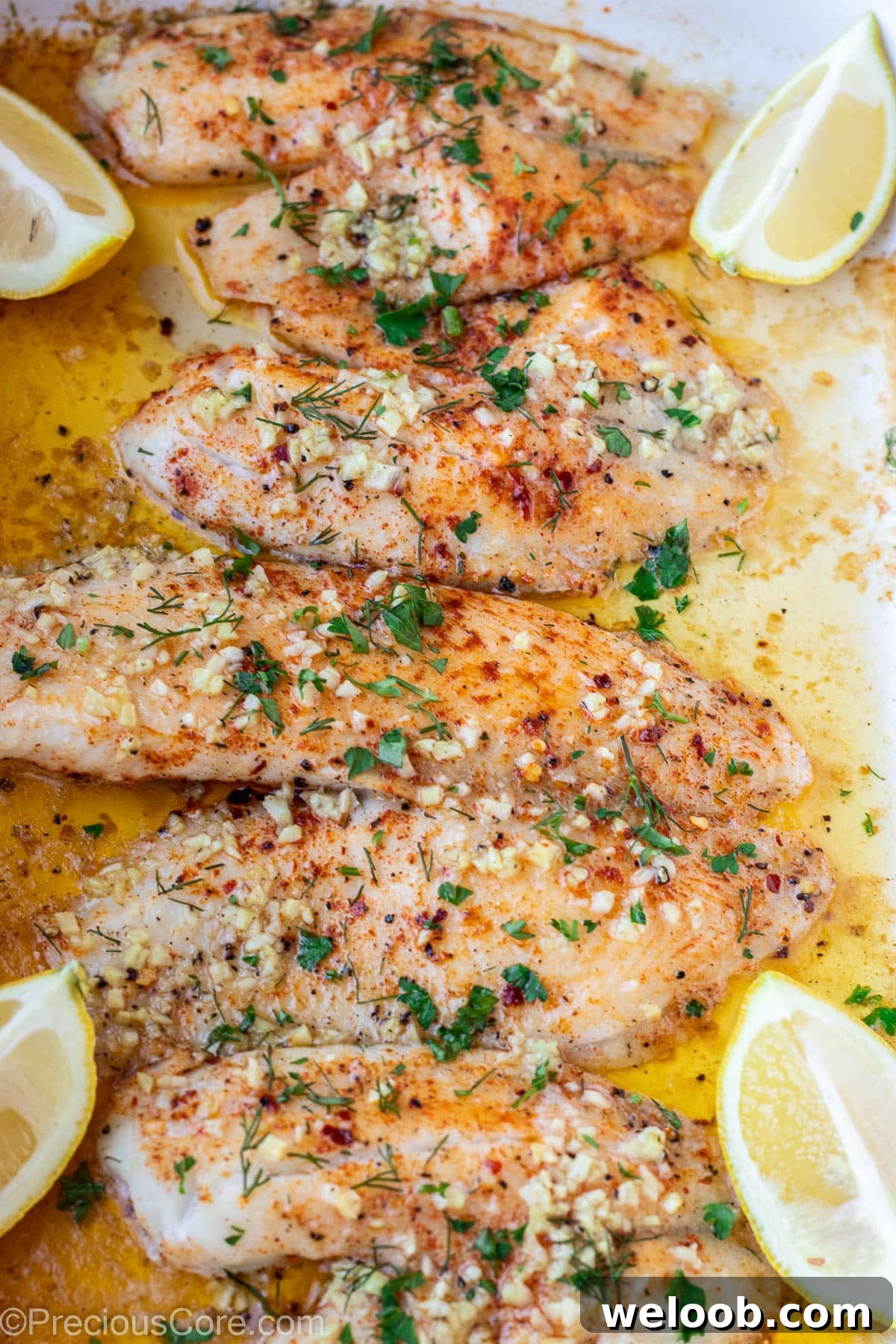 4 baked tilapia fillets in a pan.