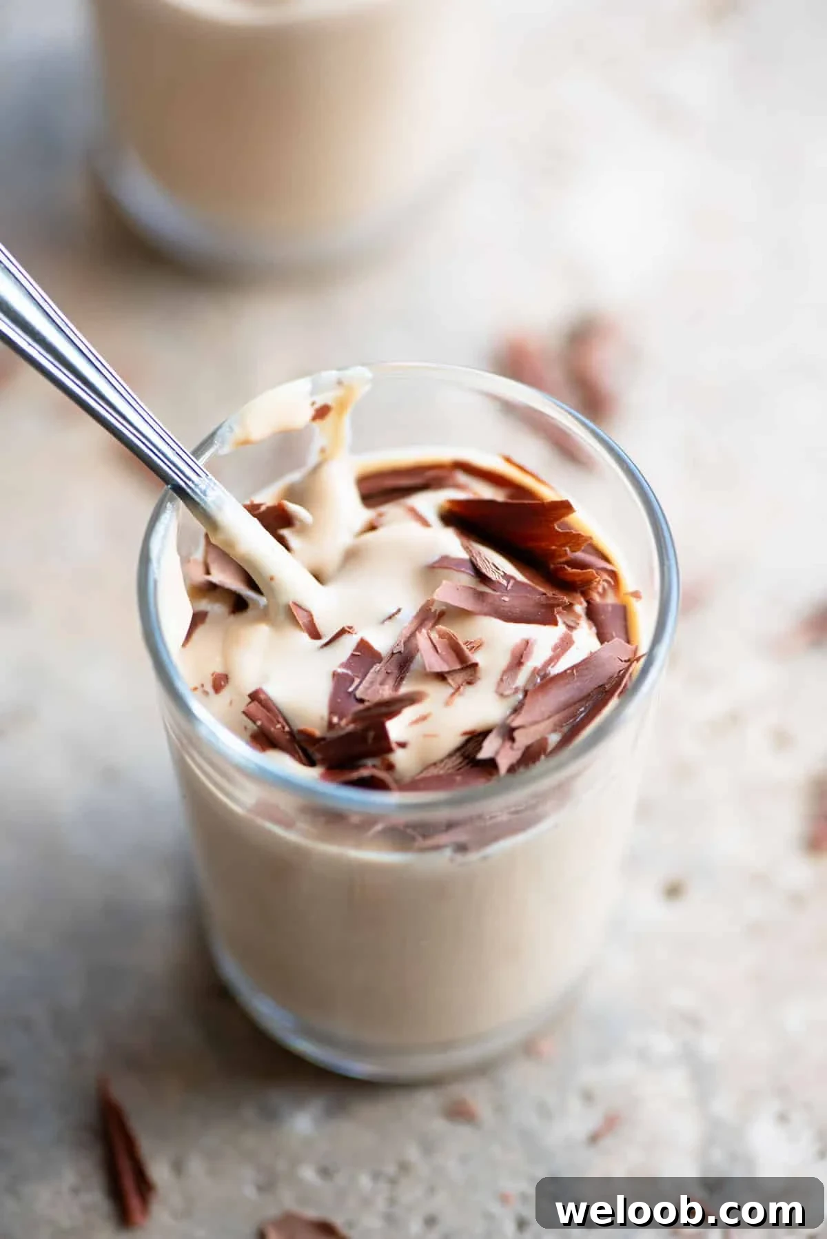 A close up of ricotta and coffee in a small glass with a spoon inside.