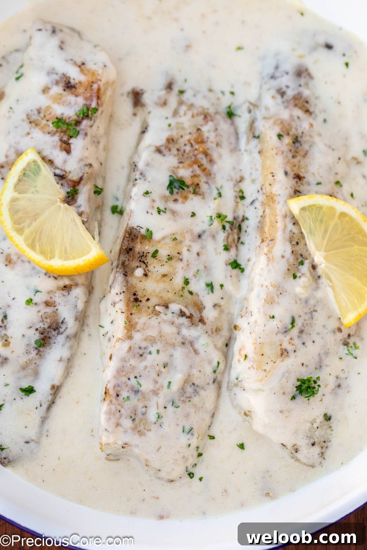 Fish in white sauce with lemon slices.
