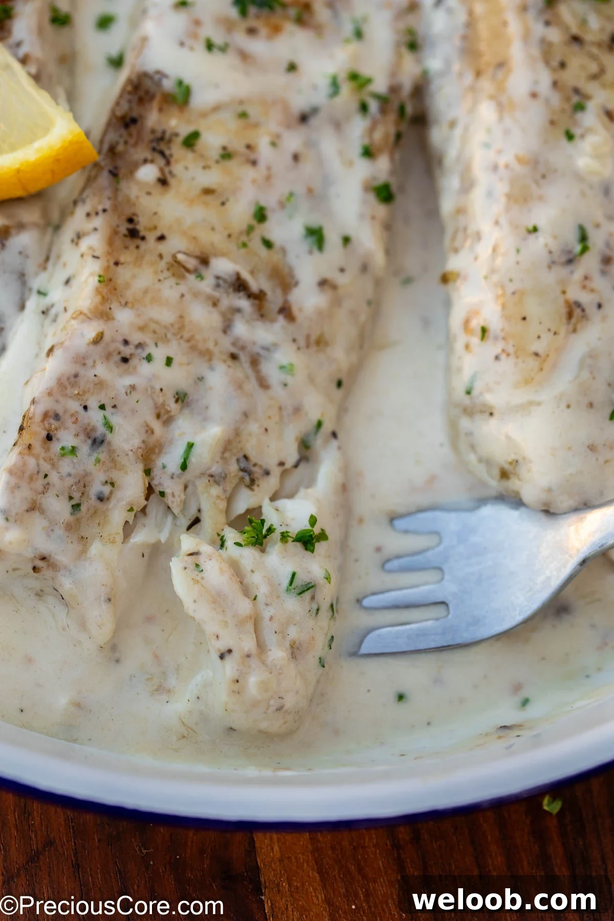 Dipping fork into fish in white sauce.