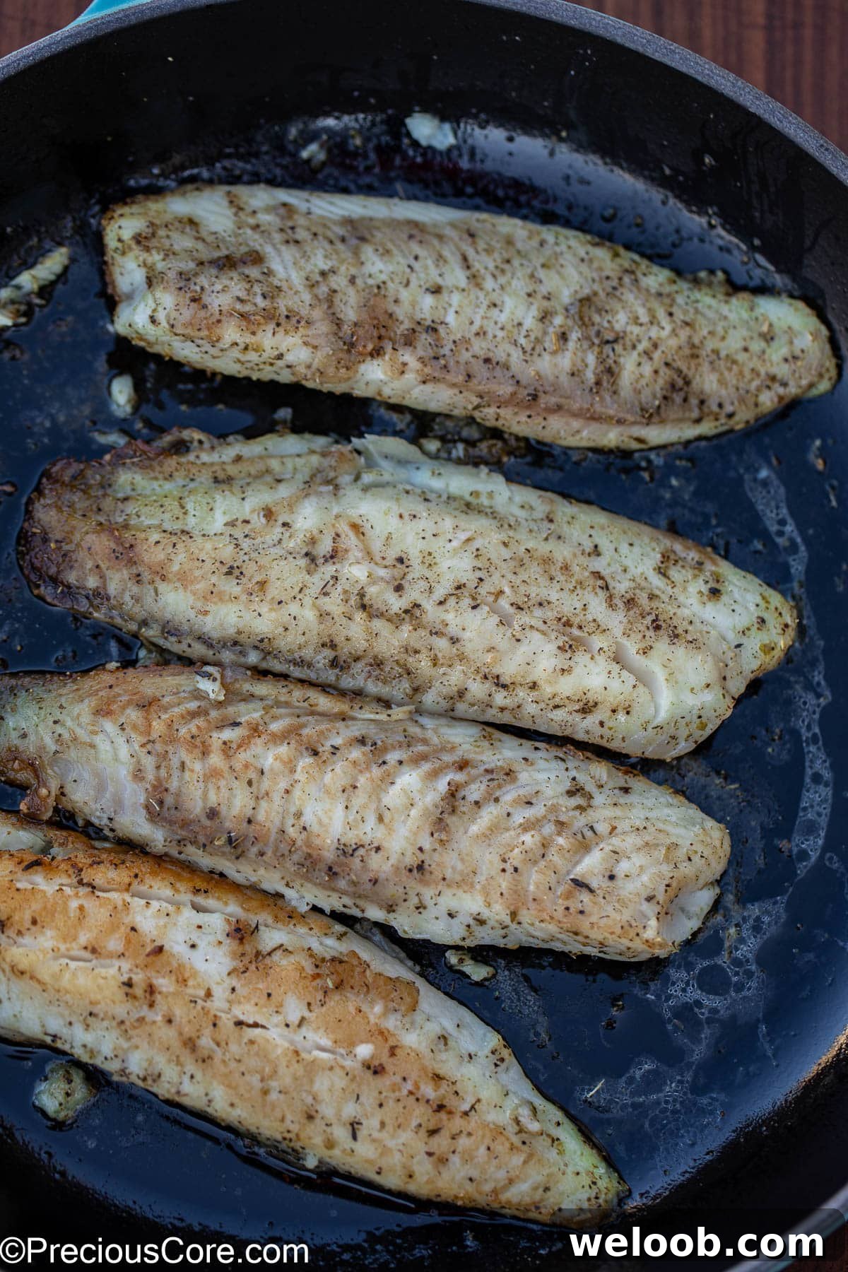Seasoned and cooked fish in pan.