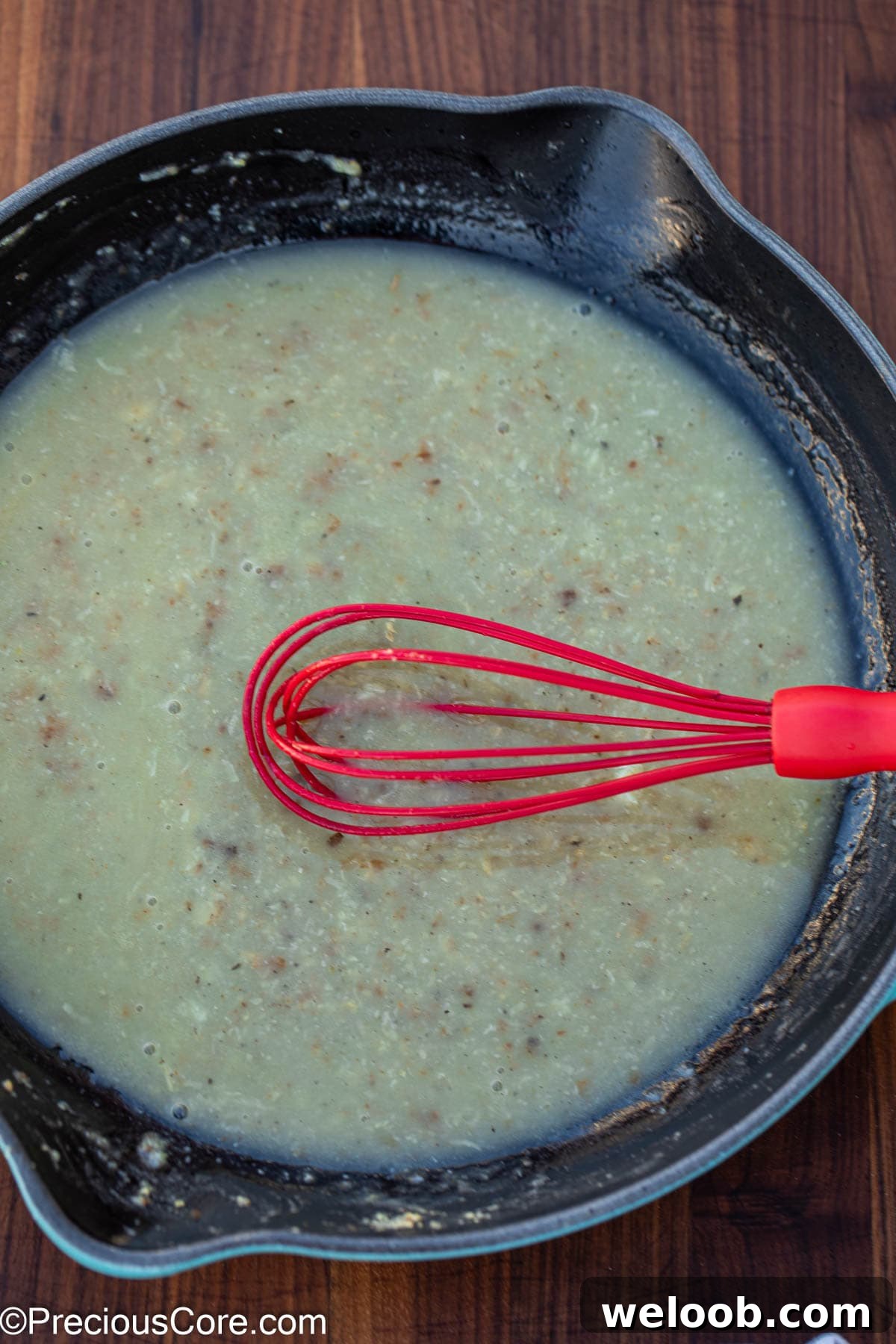 Mixing white sauce with a whisk.
