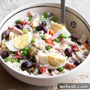 A cropped square image of an Italian rice salad in a bowl topped with eggs.