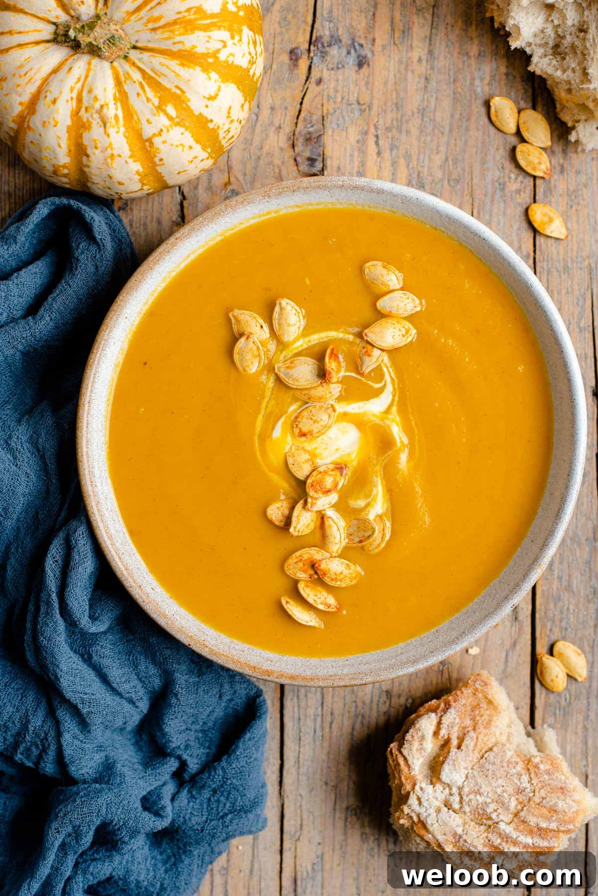 An overhead shot of a bowl of pumpkin soup topped with toasted pumpkin seeds