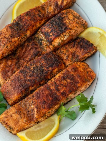 Four grilled salmon fillets on a serving platter