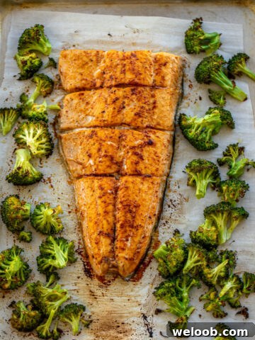 Large salmon fillet and roasted broccoli on a sheet pan