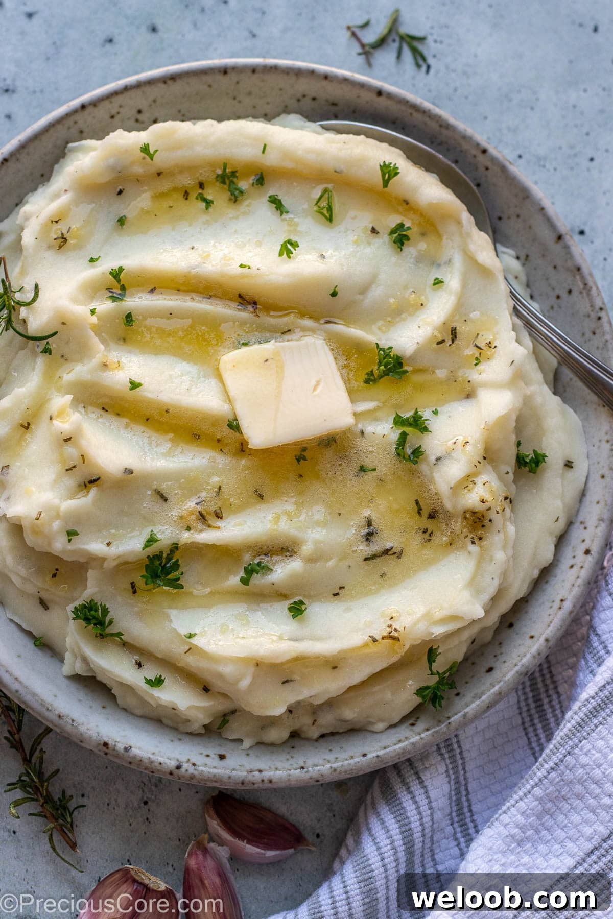 Rosemary Garlic Mashed Potatoes in a bowl topped with melted butter and parsley.