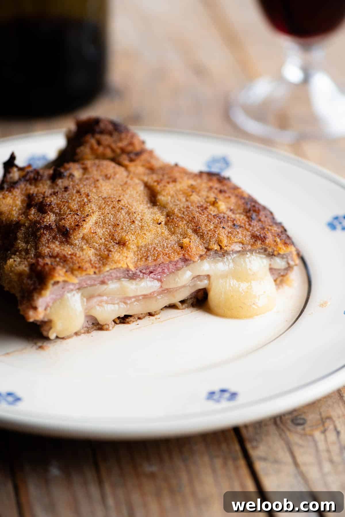 An Italian breaded veal chop (Cosoletta Valdostana) cut in half showing ham and cheese inside, oozing out.