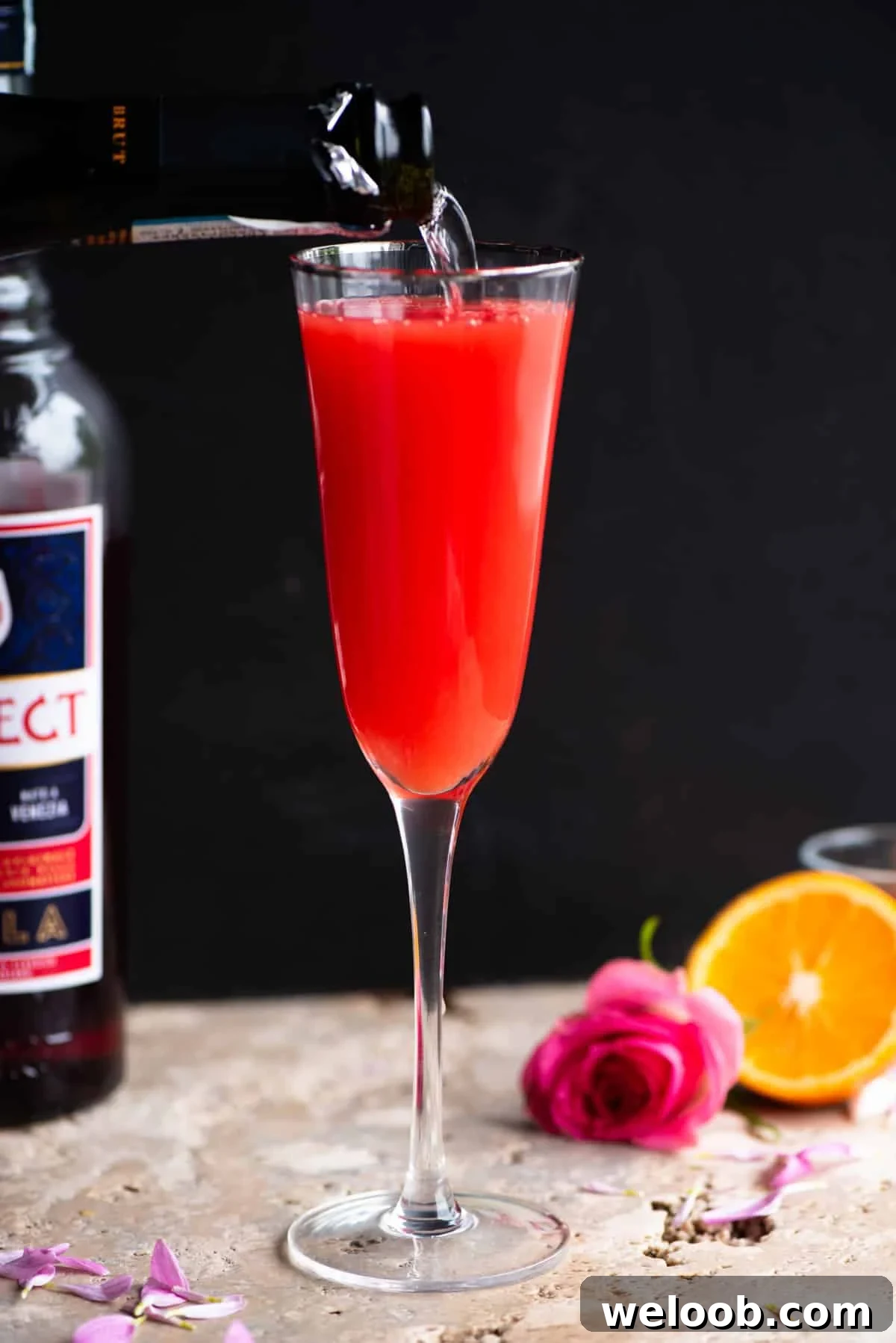 A select mimosa in a flute glass with prosecco getting poured in.