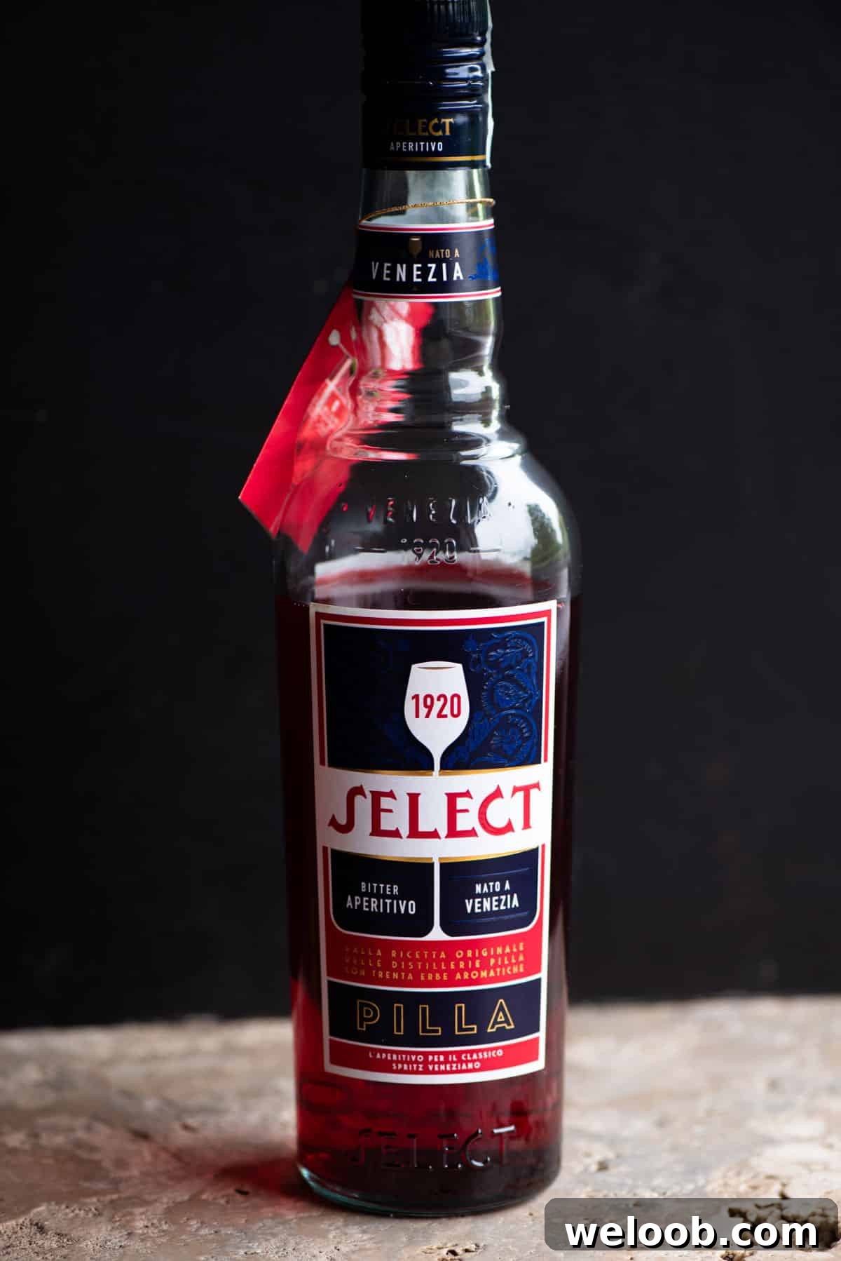 A bottle of Select Aperitivo on a stone work surface with a black background.