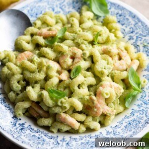 A close up of a zucchini shrimp pasta salad topped with basil.