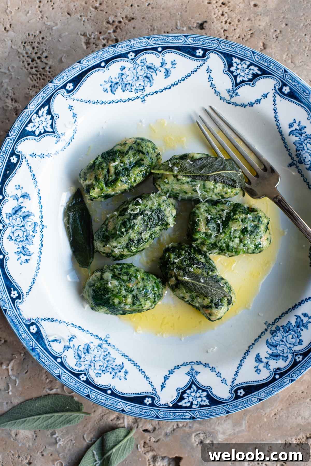 An overhead shot of Strangolapreti (Italian bread dumplings) on a blue and white plate sitting on a stone work surface.
