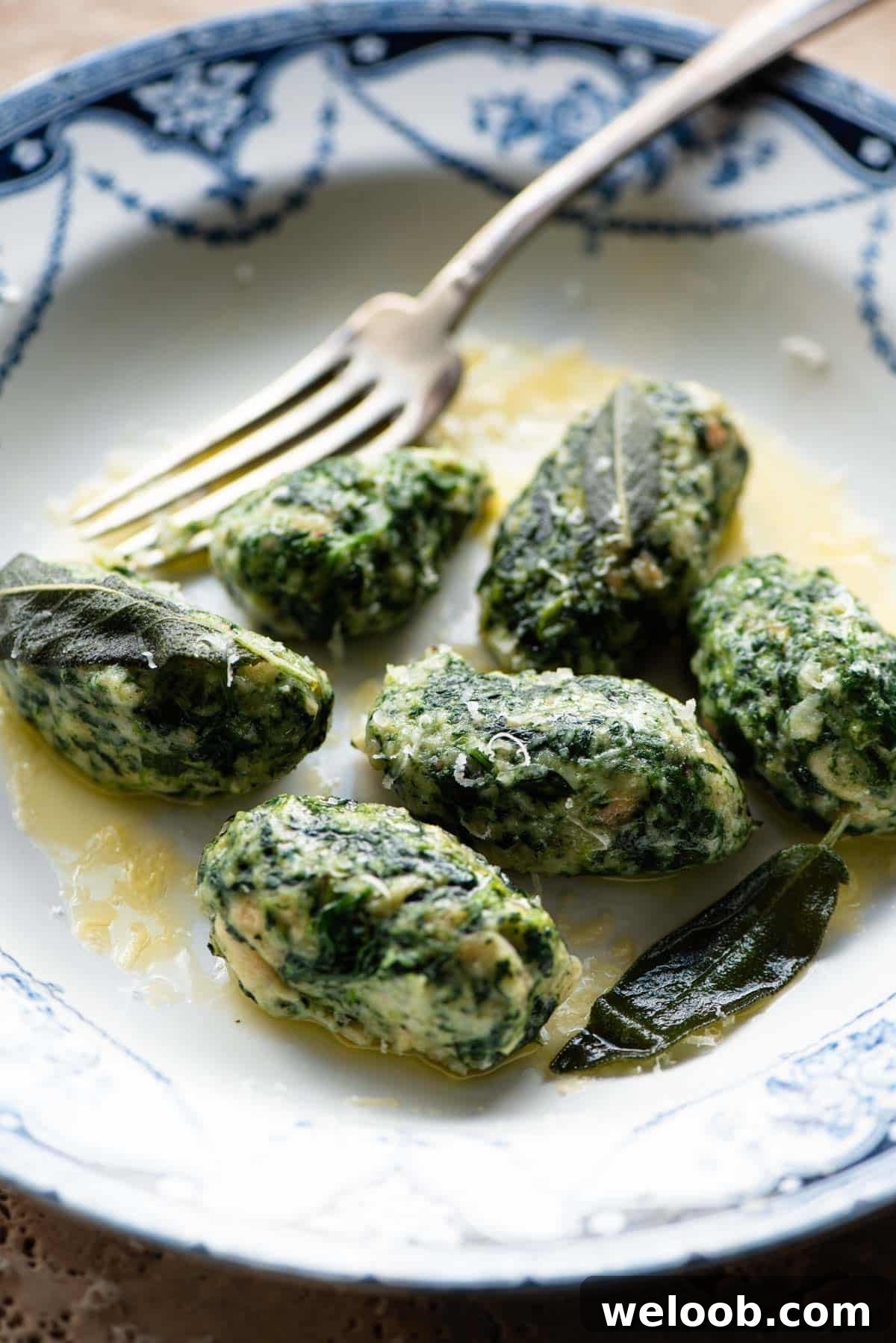 A side shot of Strangolapreti (italian bread dumplings) on a plate with butter and sage.