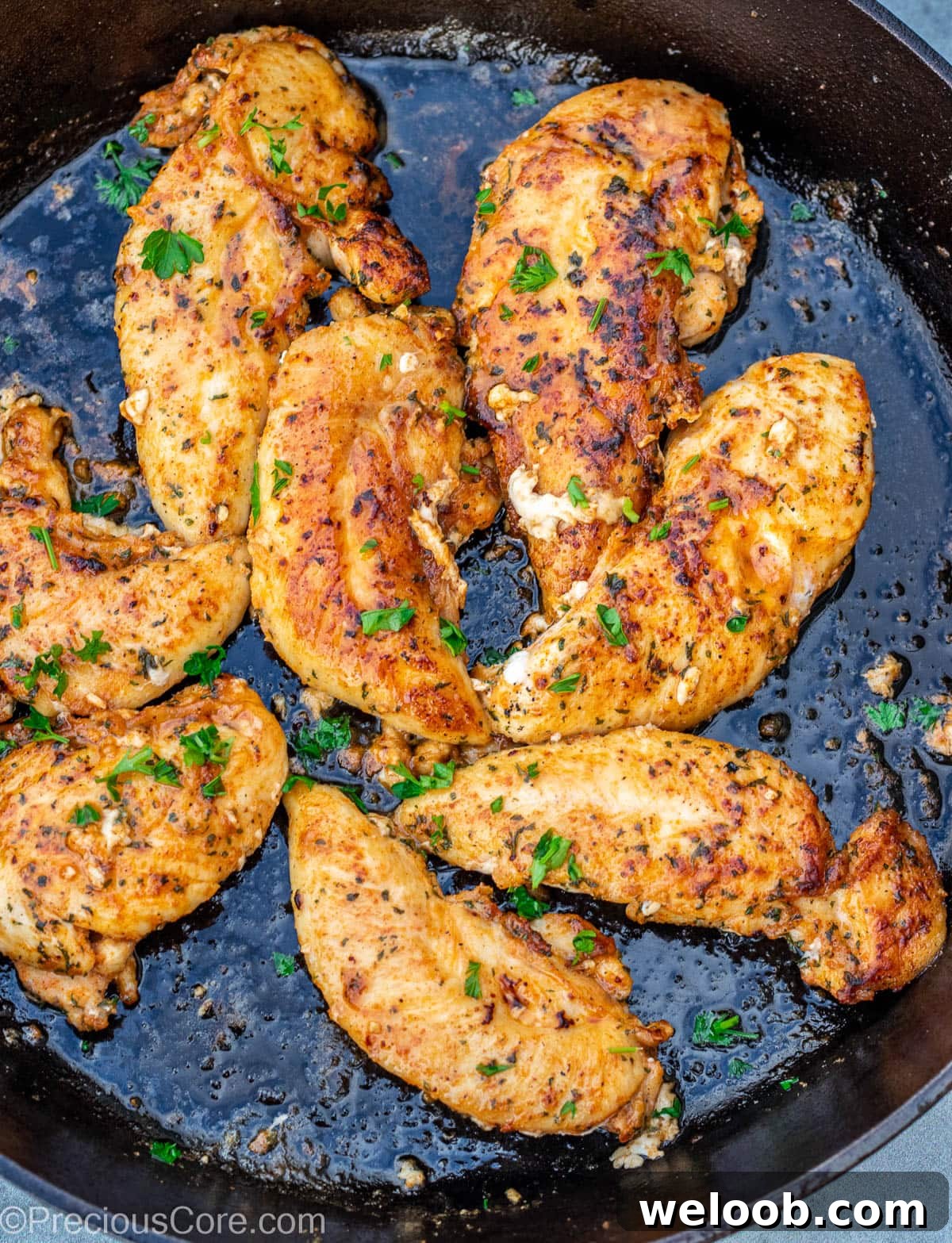 Chicken tenderloins cooking in a cast iron skillet.