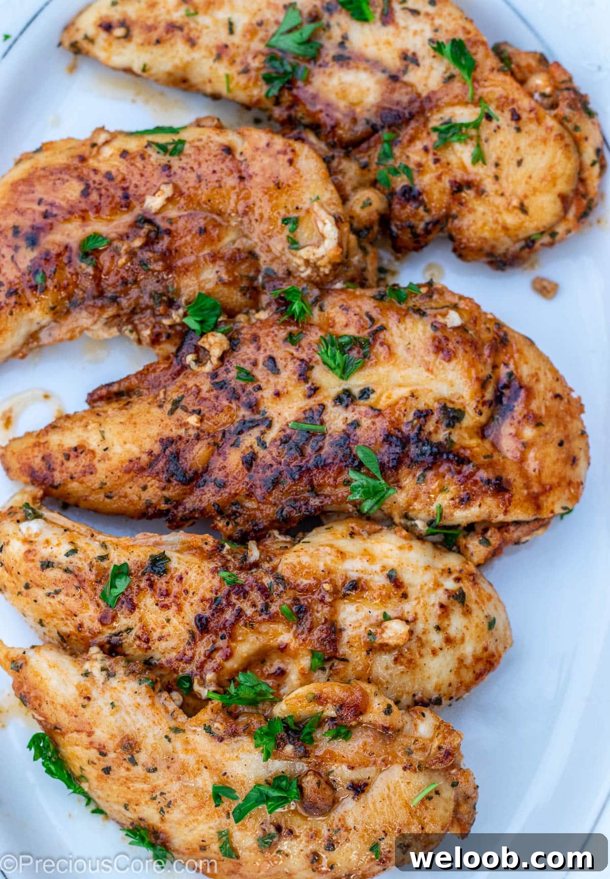Pan seared chicken tenders on a white platter.
