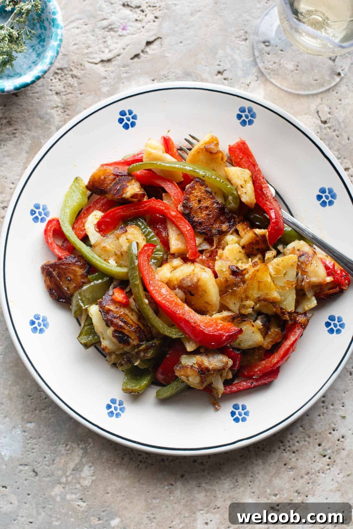 An overhead shot of peppers and potatoes on a plate with a fork at the side.