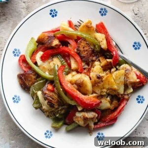 A cropped overhead shot of potatoes and peppers on a traditional Italian painted terracotta plate.