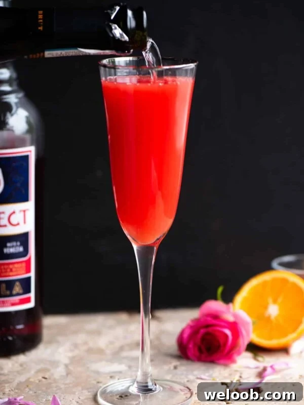 A select mimosa in a flute glass with prosecco getting poured in.