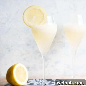 A close up of an Italian Sgroppino cocktail in a flute glass with a slice of lemon on the side.