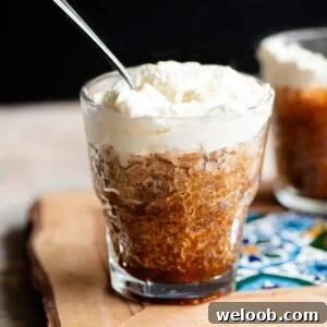 A cropped square image of a small glass filled with coffee granita and topped with whipped cream.