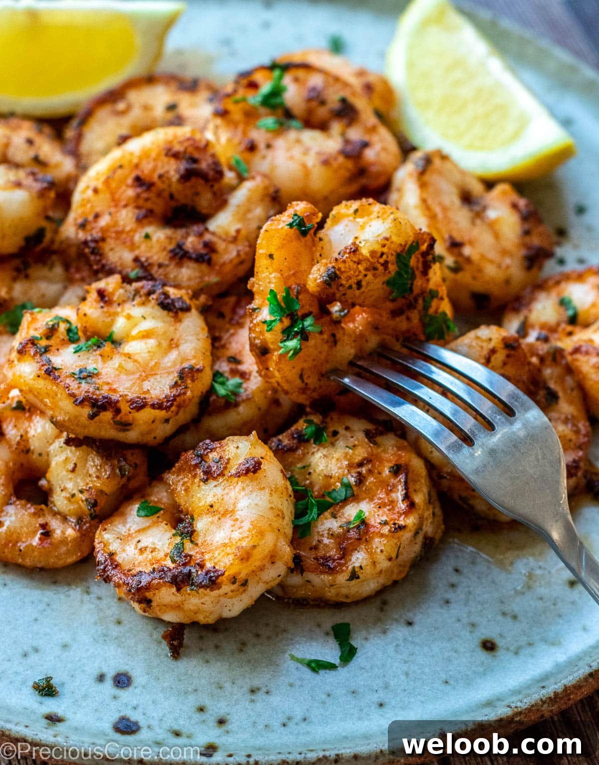 Shrimp on a plate with lemon wedges.