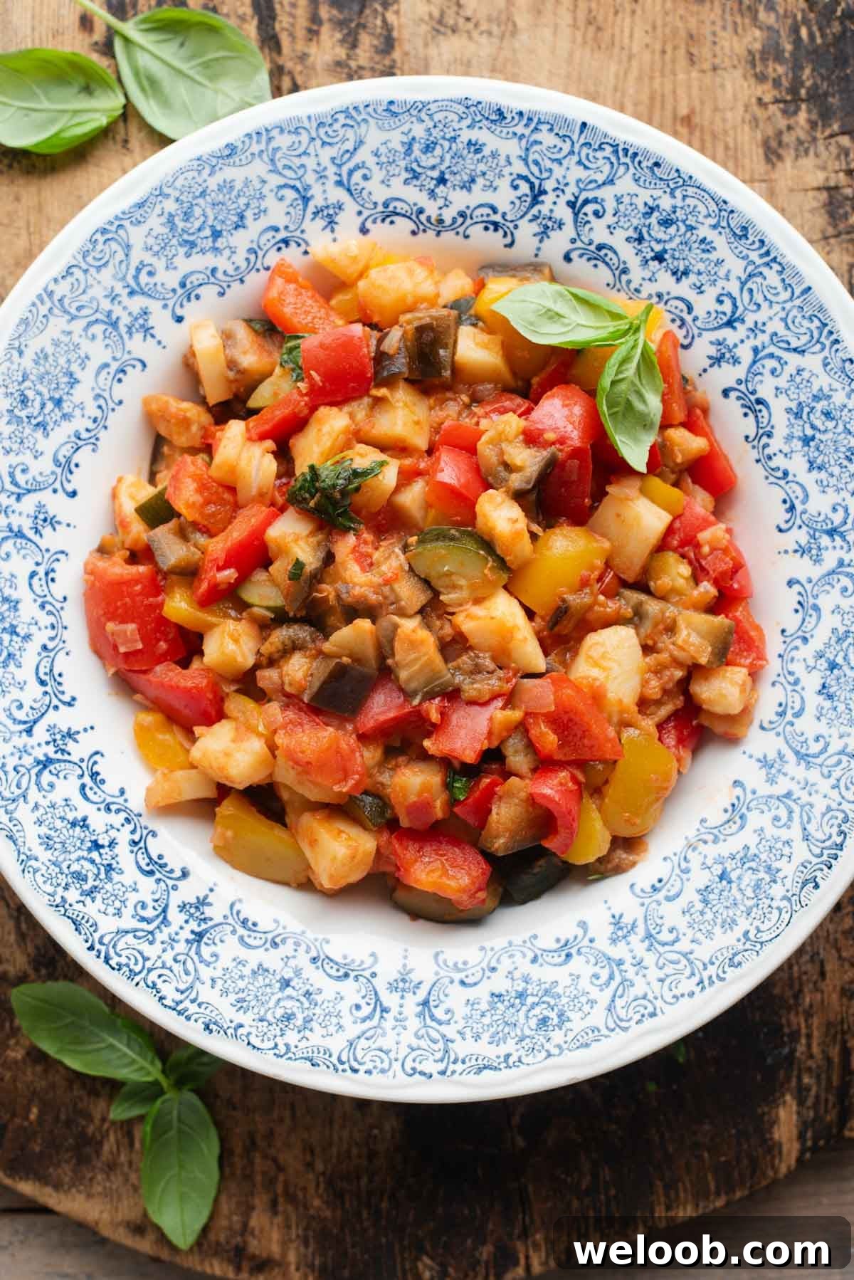 An overhead shot of Ciambotta (Italian vegetable stew) in a blue bowl, the background is wooden.