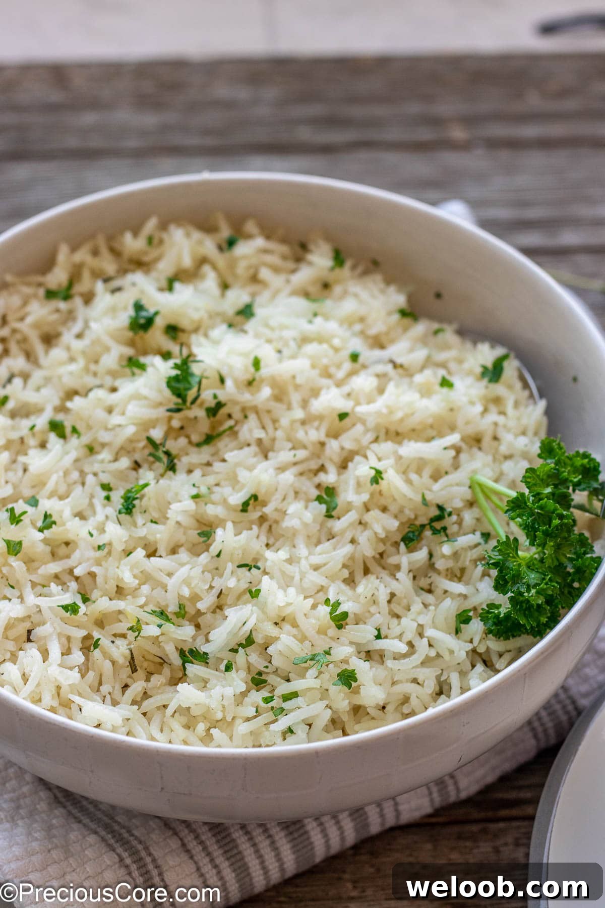 A bowl of garlic herb rice topped with minced fresh parsley.