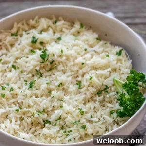 A bowl of garlic herb rice topped with minced fresh parsley.