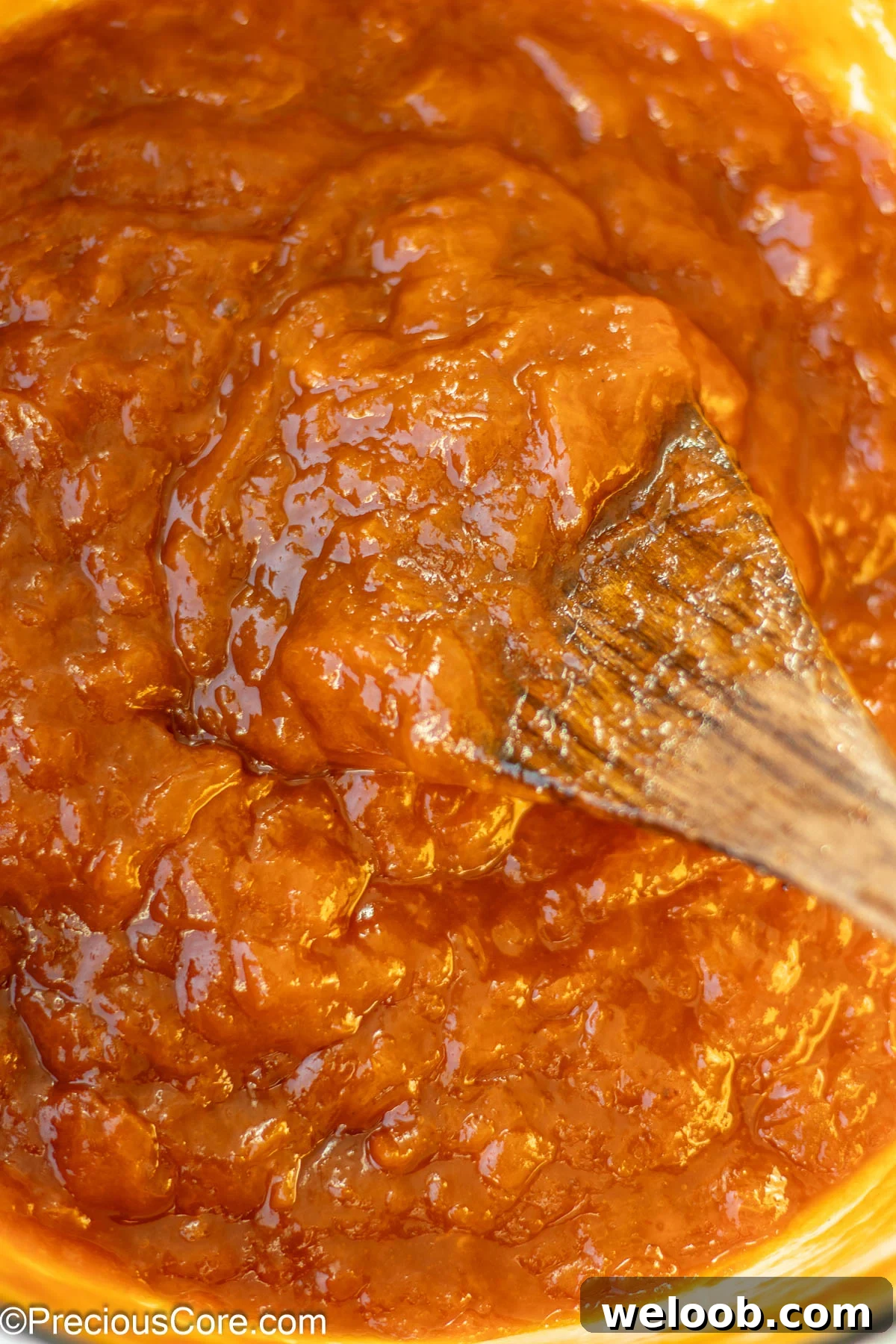 Fully cooked food preserves in a pot with a wooden spoon.