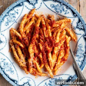 An overhead shot of a spicy tomato Nduja pasta in a blue and white bowl.