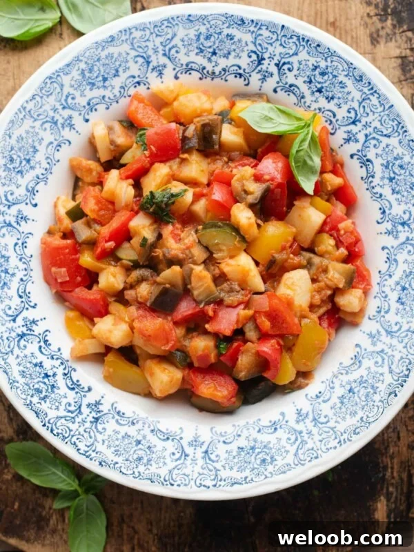 An overhead shot of Ciambotta (Italian vegetable stew) in a blue bowl, the background is wooden.
