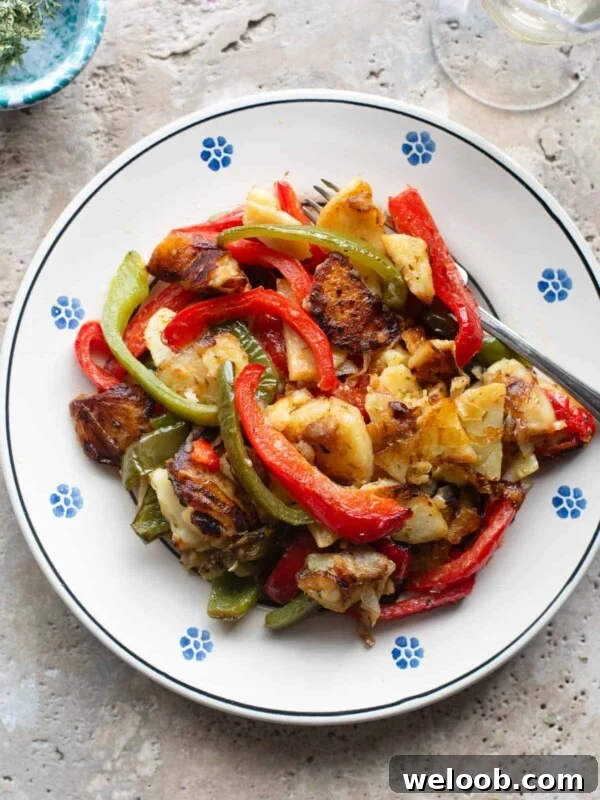 An overhead shot of peppers and potatoes on a plate with a fork at the side.