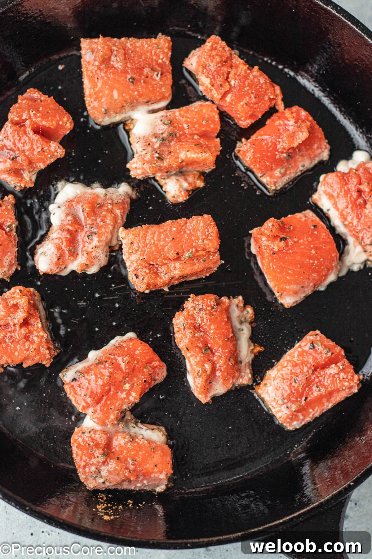 Salmon bites in a cast iron skillet.