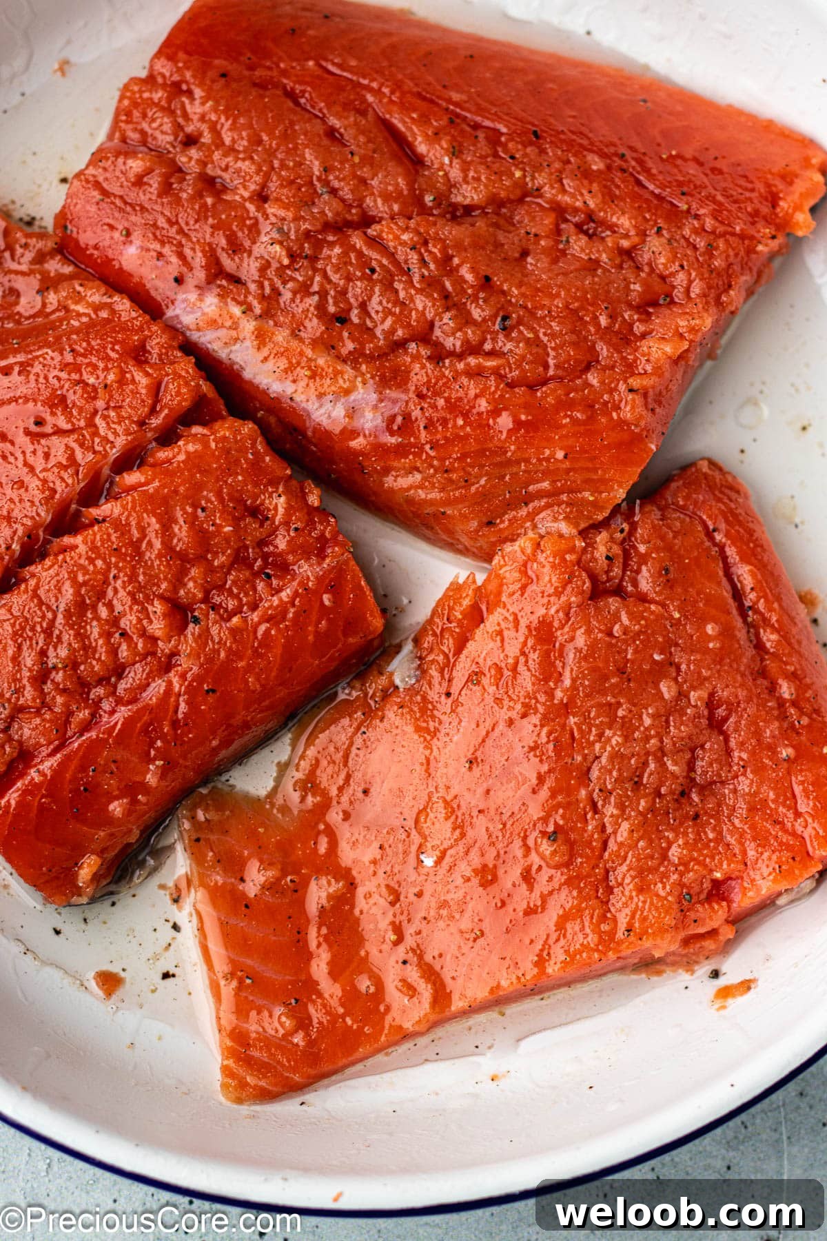 Seasoned salmon in a white bowl.