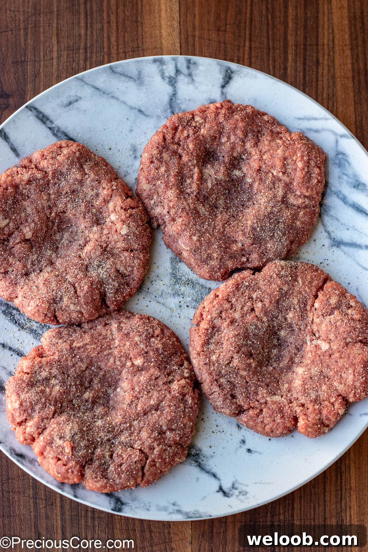 Seasoned burger patties on a plate.