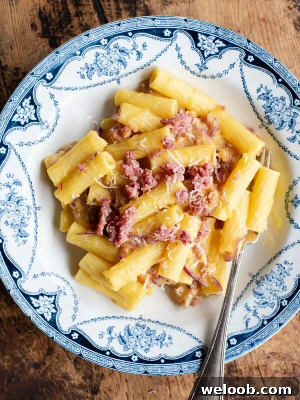 An ovehead shot of a bowl of pasta with potato, saffron and sausage, the background is wooden.