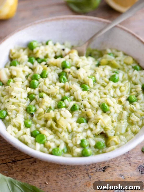 A side shot of a pea and pesto risotto in a bowl in a wooden surface with a fork at the side