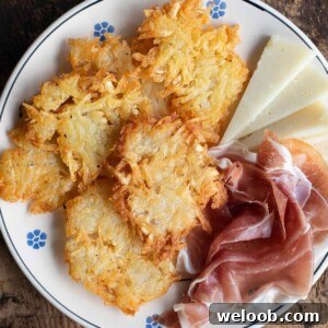 A close up cropped image of Tortei di Patate fritters on a plate with meat and cheese.