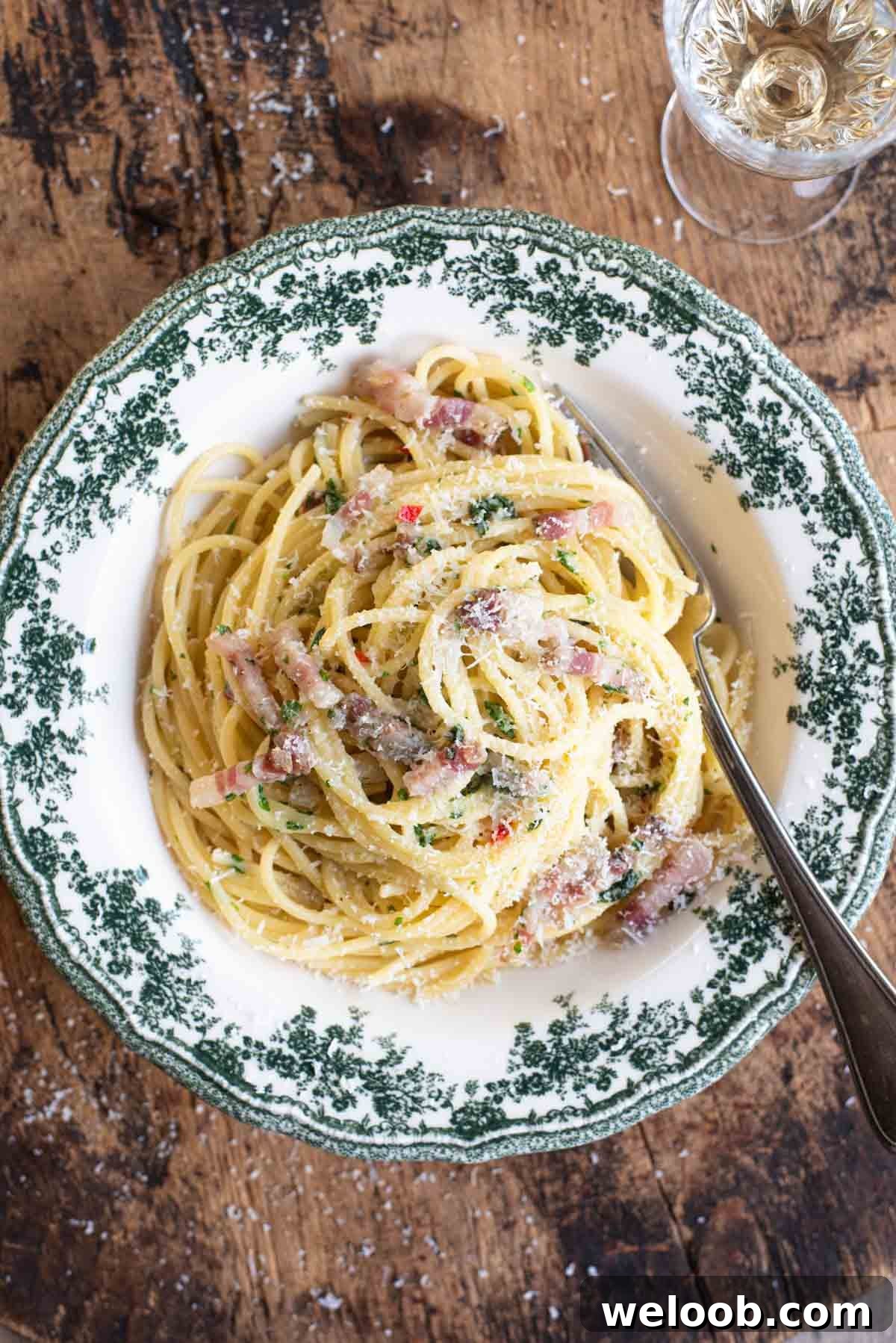 An overhead shot of spaghetti alla Molisana in a green patterned bowl on a wooden background.