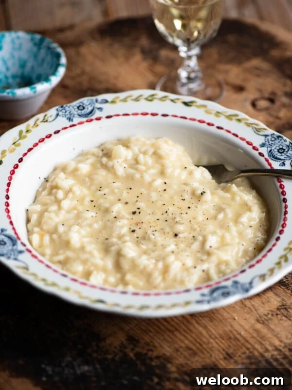 A bowl of cheesy Risotto alla valdostana sitting on a wooden board.