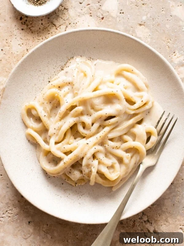 An overhead shot of pici pasta with cacio e pepe sauce on a plate