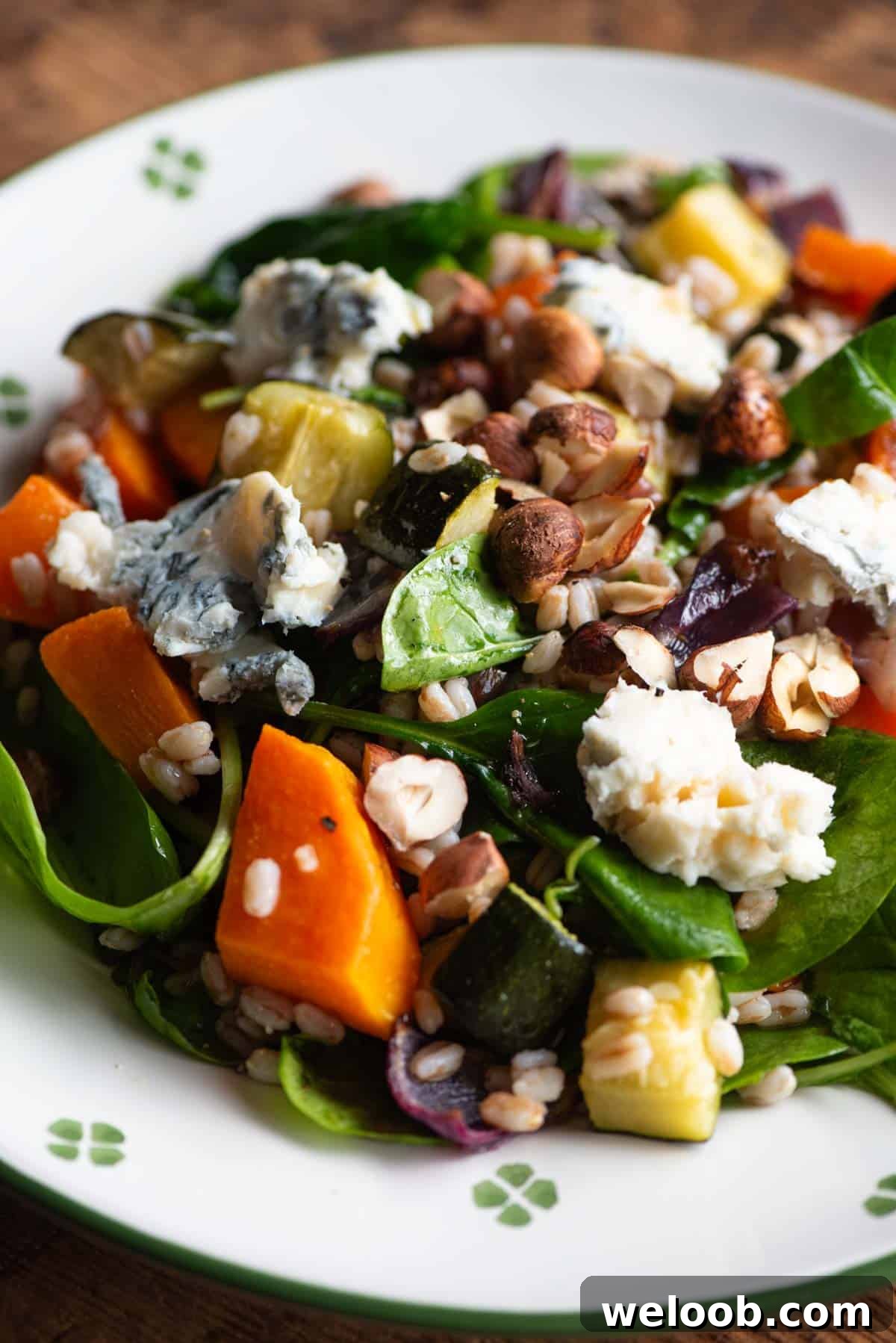 A close up of a farro salad on a plate with butternut squash, spinach and gorgonzoal.