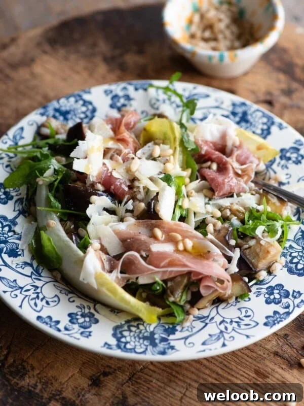 A close up of an eggplant and farro salad on a blue patterned plate on a wooden table.