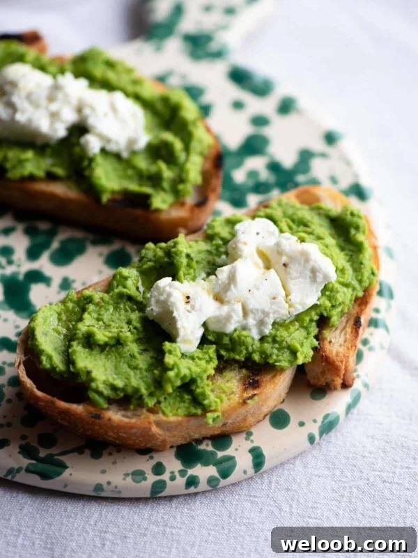 A close up of bruschetta topped with pea pesto and goat cheese on a ceramic serving board.